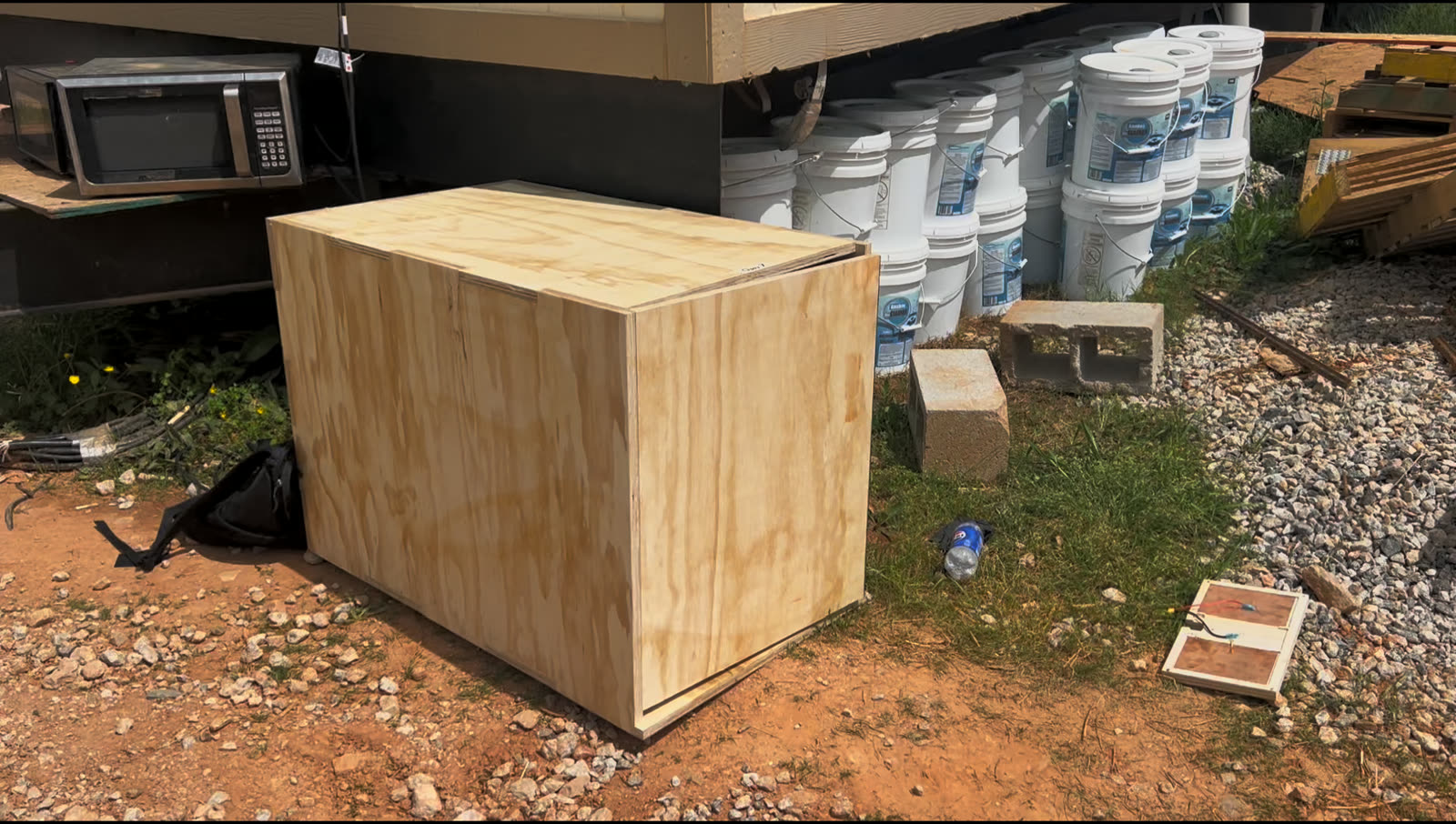 The original plywood charging hub sitting on gravel beside a building